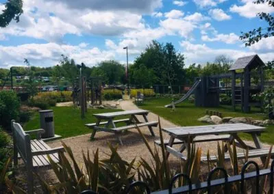 Park with picnic bench in the foreground and playground apparatus in the background